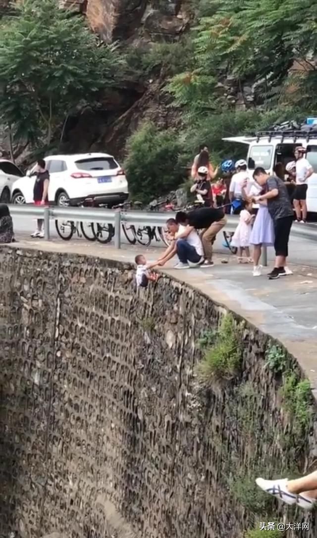 徒手|心真大！一家长竟徒手将孩子挂在峭壁上拍照，还故意抖动